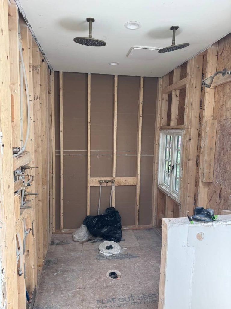 Bathroom stripped to the framing with plumbing rough-in and two ceiling shower drops installed.
