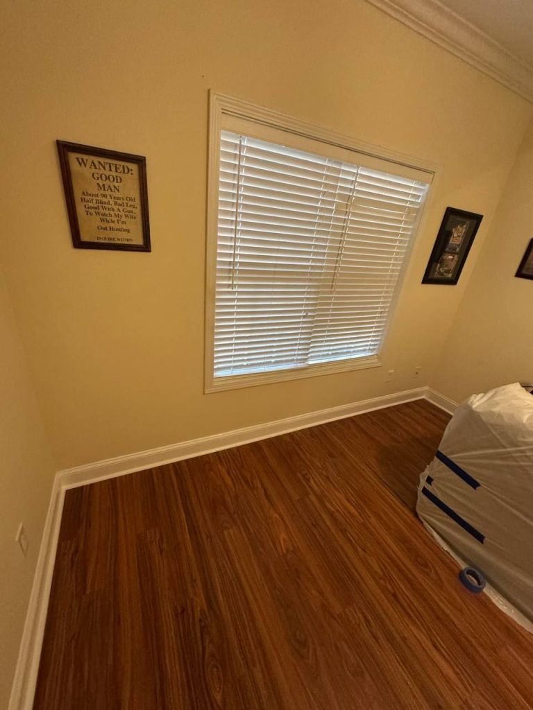 The same room finished with a new wood plank floor, rebuilt and repainted walls and reset baseboards.
