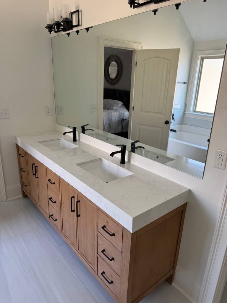 Double vanity in light oak with a quartz countertop, two undermount sinks and matte black faucets.